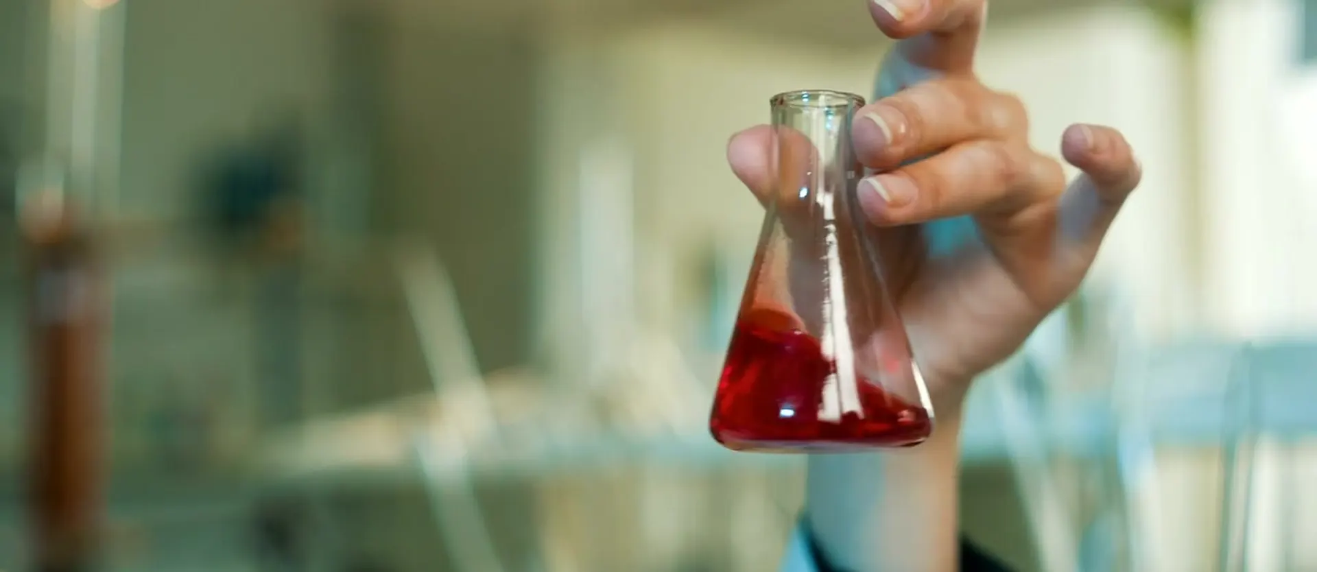 A gloved hand holding a laboratory flask