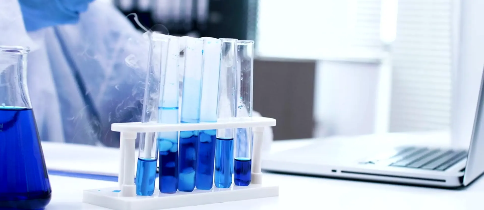 Glass vials with blue liquid on a laboratory bench